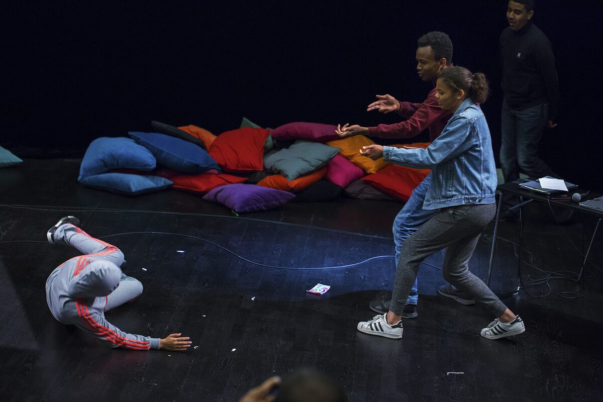 Young people performing a Forum Theatre scene on stage, rehearsing intervention and bystander action